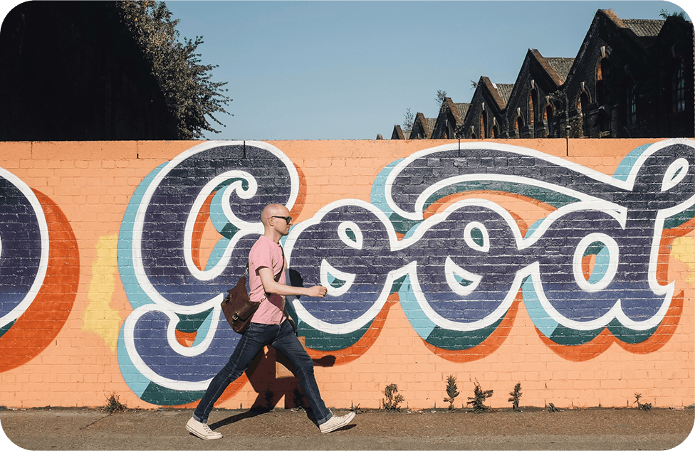 Man walking in a street past mural